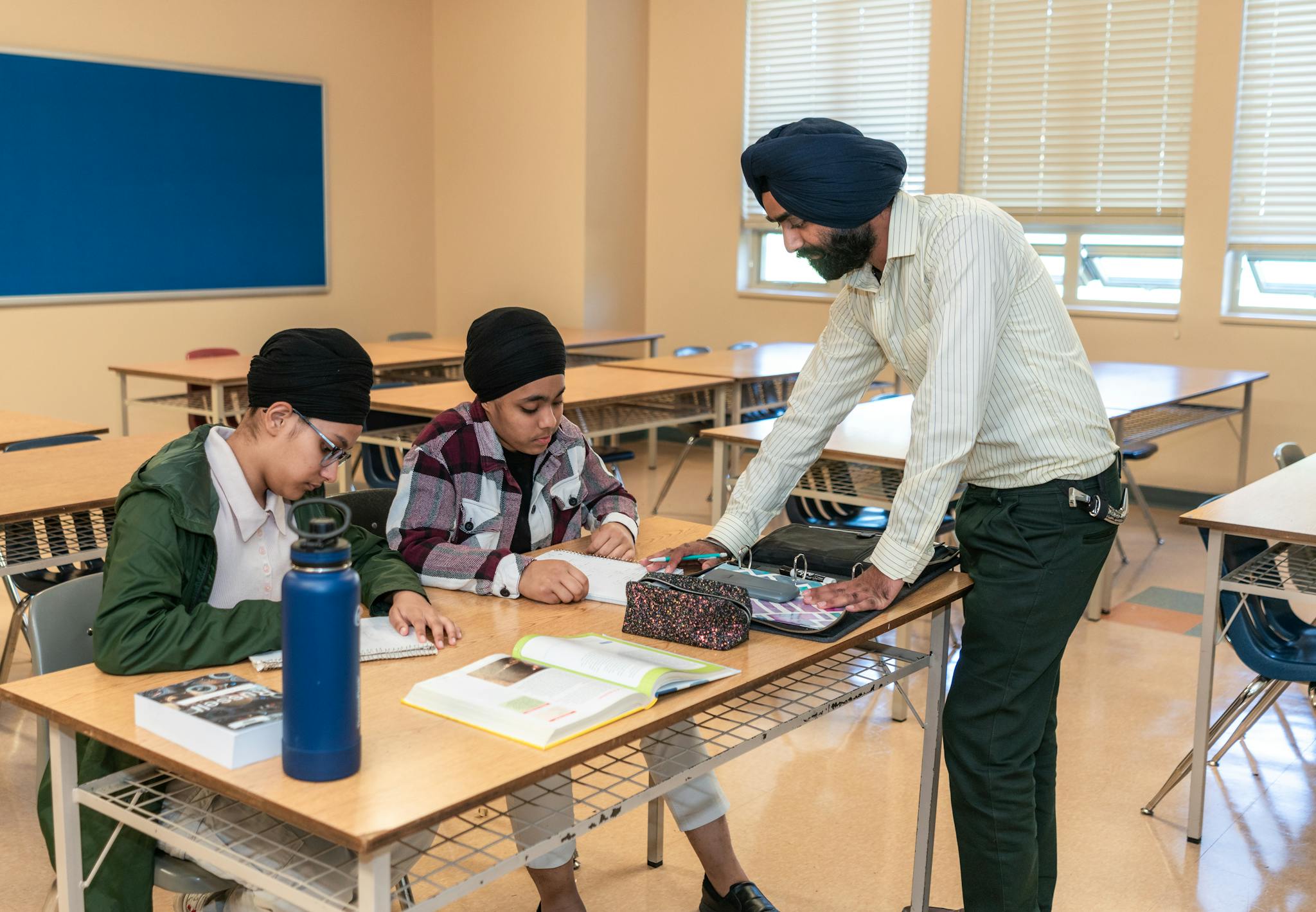 Teacher helping students with schoolwork in a modern classroom environment.